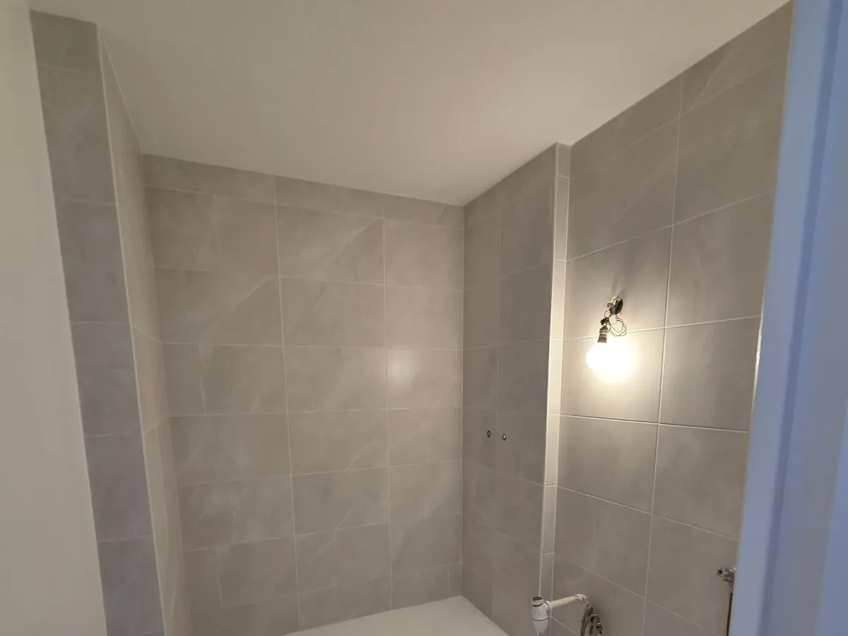 Douche à l'italienne dont l'évacuation a été reprise sous le receveur