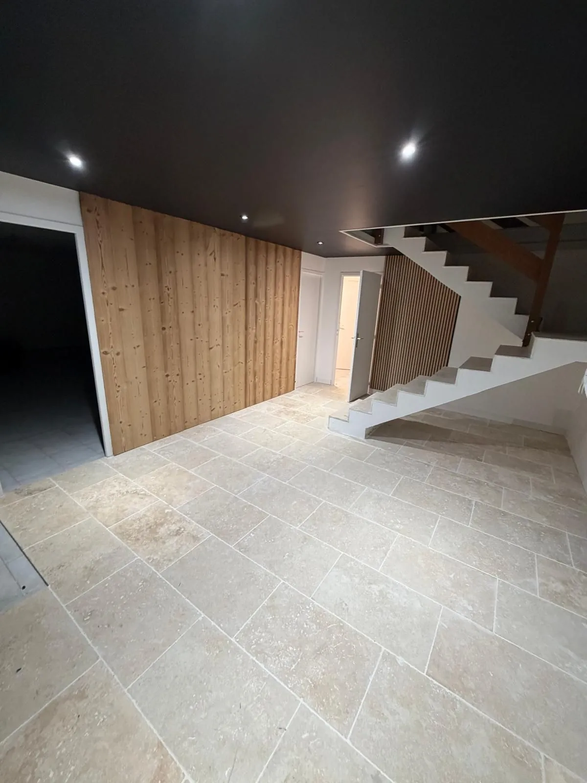 Entrée rénovée par JGR TECHNIBAT : sol en travertin, bardage bois et escalier béton